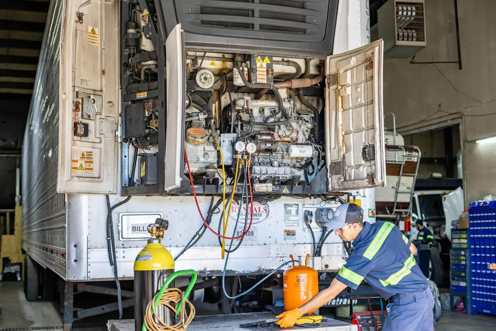 Technician recharging a transport refrigeration reefer unit with manifold gauges